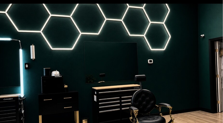 Black and gold barber chair at the Emerald Edge cutting station beneath glowing hexagon lights.