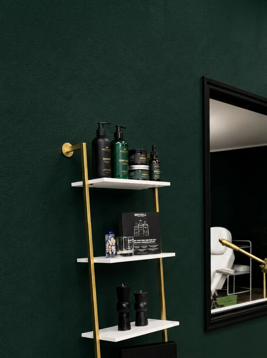 Gold display shelf stocked with professional hair and beard products beside a black-framed mirror.