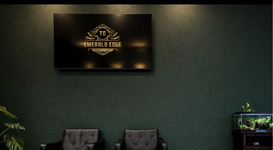 Two black leather waiting chairs beneath a television on a deep emerald wall.